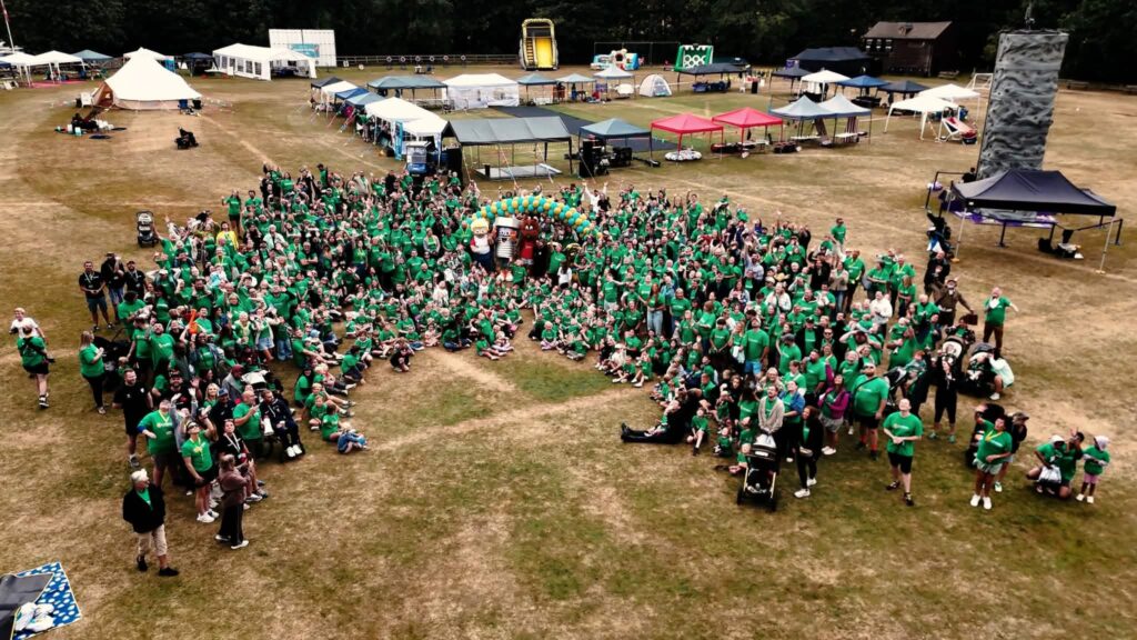 a large group of people in a field all wearing green t shirts